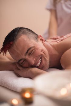 Positive young man having a back massage in a spa center