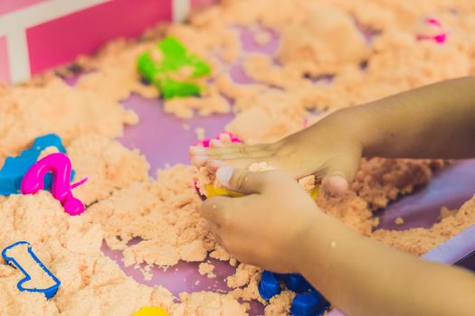 Boy playing with kinetic sand in preschool. The development of fine motor concept. Creativity Game concept.