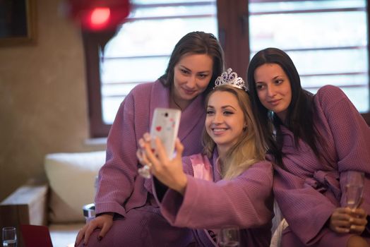 three young beautiful happy girls doing Selfy on bachelorette party at a luxury spa with champagne