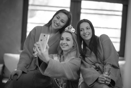 three young beautiful happy girls doing Selfy on bachelorette party at a luxury spa with champagne