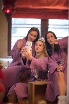 three young beautiful happy girls doing Selfy on bachelorette party at a luxury spa with champagne