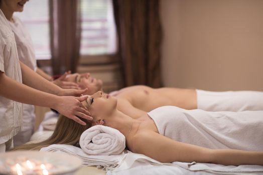 happy young beautiful couple enjoying head massage at the spa