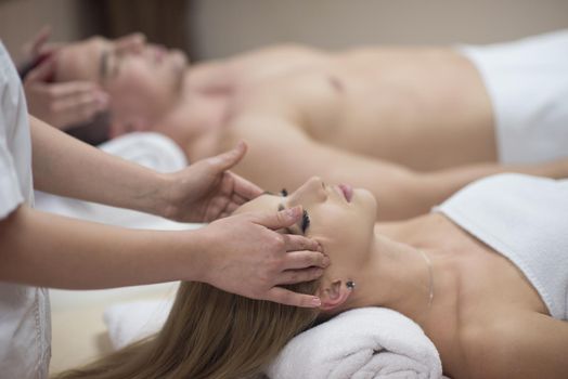 happy young beautiful couple enjoying head massage at the spa