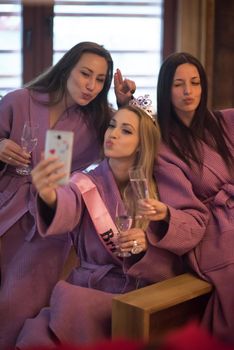 three young beautiful happy girls doing Selfy on bachelorette party at a luxury spa with champagne