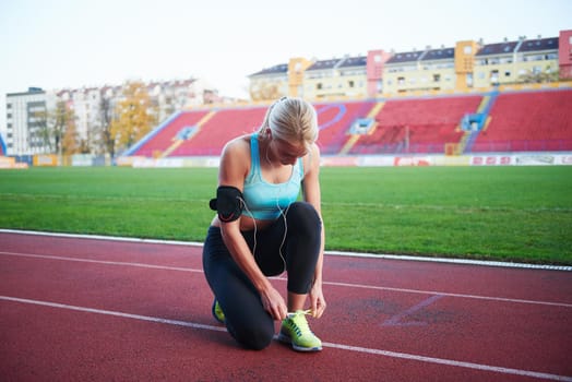 young runner sporty woman relaxing and stretching on athletic race track