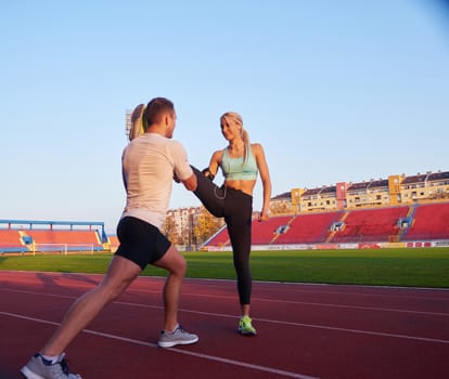 young runner sporty woman relaxing and stretching on athletic race track