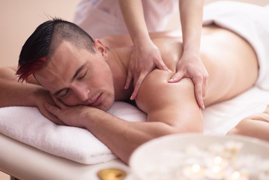 Positive young man having a back massage in a spa center