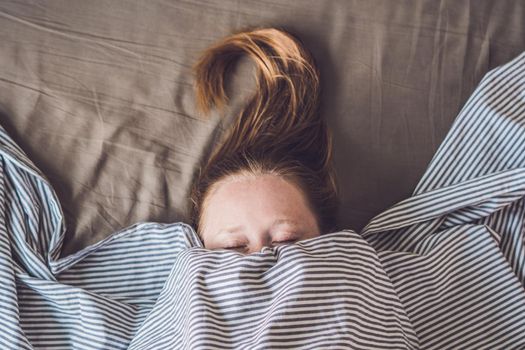 Beautiful young woman lying down in bed and sleeping, top view. Do not get enough sleep concept.