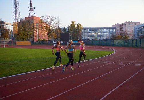 athlete woman group  running on athletics race track on soccer stadium and representing competition and leadership concept in sport