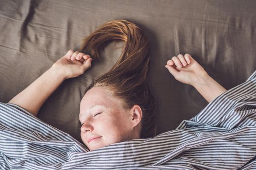 Beautiful young woman lying down in bed and sleeping, top view. Do not get enough sleep concept.