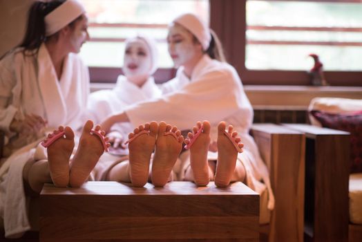 group of famale friends in spa have fun, celebrate bachelorette party with face mask