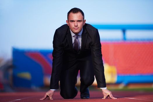 business man in start position ready to run and sprint on athletics racing track