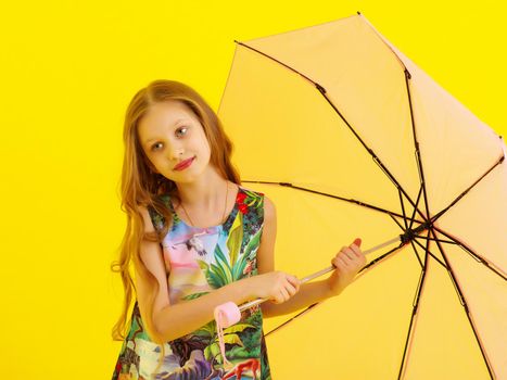 A beautiful little girl hid under an umbrella. The concept of summer vacation, style and fashion. Isolated.