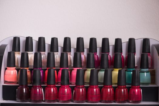 Set of different bottles of nail polish in the shelf in the beauty salon