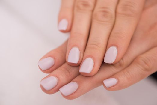 Beautiful fingers with french manicure on the towel. Manicure in a beauty salon.