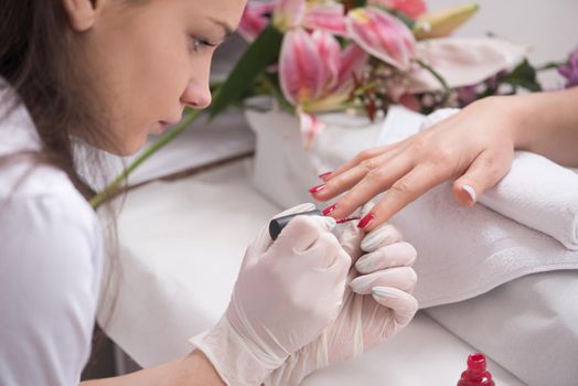 Woman hands receiving a manicure in beauty salon. Nail filing. Close up, selective focus.