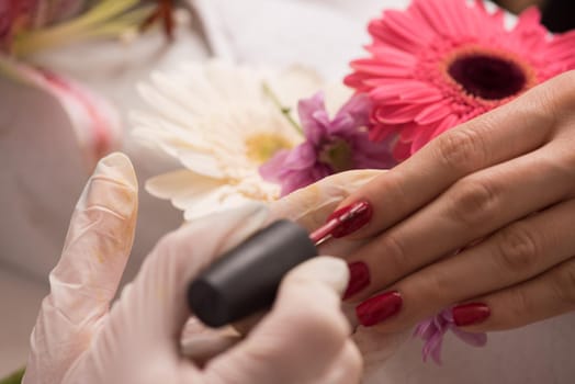 Woman hands receiving a manicure in beauty salon. Nail filing. Close up, selective focus.