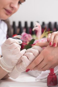 Woman hands receiving a manicure in beauty salon. Nail filing. Close up, selective focus.