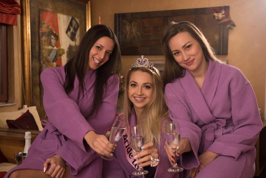 three young beautiful happy girls have a bachelor party at a luxury spa with champagne