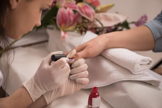 Woman hands receiving a manicure in beauty salon. Nail filing. Close up, selective focus.