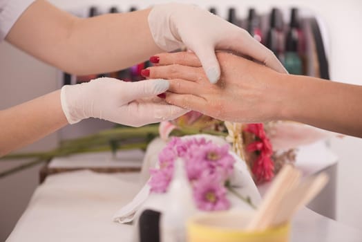 Woman hands receiving a manicure in beauty salon. Nail filing. Close up, selective focus.