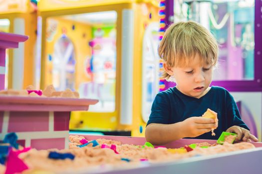 Boy playing with kinetic sand in preschool. The development of fine motor concept. Creativity Game concept.