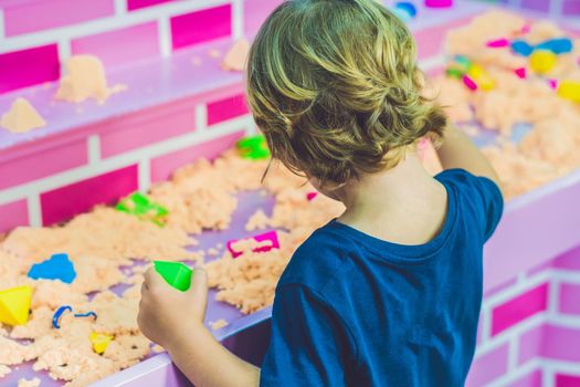 Boy playing with kinetic sand in preschool. The development of fine motor concept. Creativity Game concept.