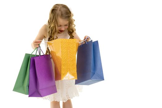 A cheerful little girl is shopping in a store with large, multi-colored paper bags. The concept of holidays, advertising sales. Isolated on white background.