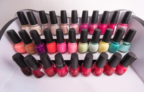 Set of different bottles of nail polish in the shelf in the beauty salon