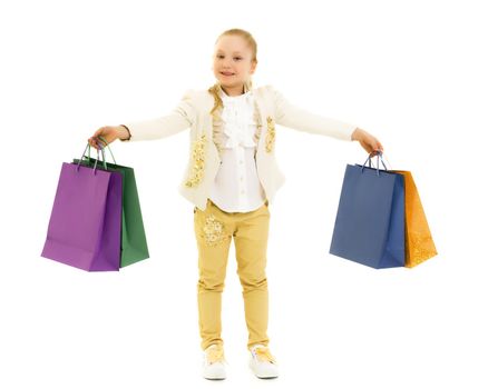 A cheerful little girl is shopping in a store with large, multi-colored paper bags. The concept of holidays, advertising sales. Isolated on white background.