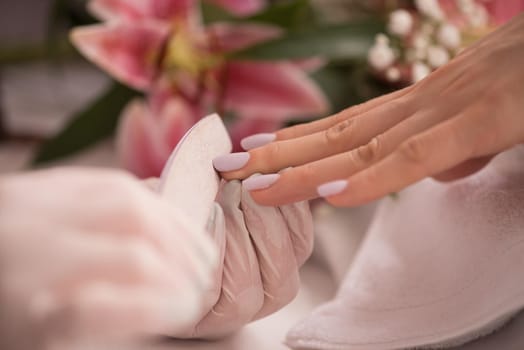 Woman hands receiving a manicure in beauty salon. Nail filing. Close up, selective focus.