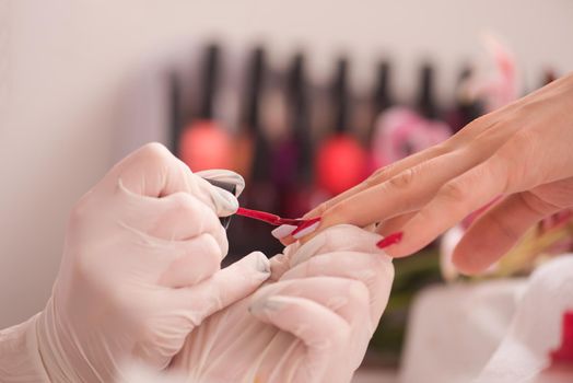 Woman hands receiving a manicure in beauty salon. Nail filing. Close up, selective focus.