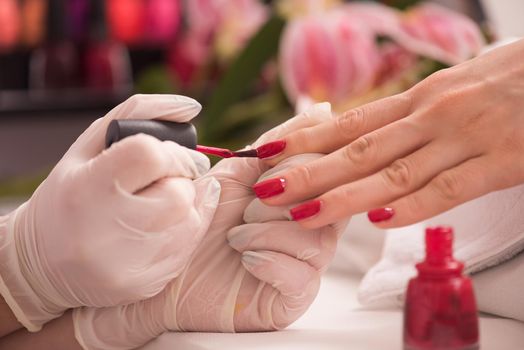 Woman hands receiving a manicure in beauty salon. Nail filing. Close up, selective focus.