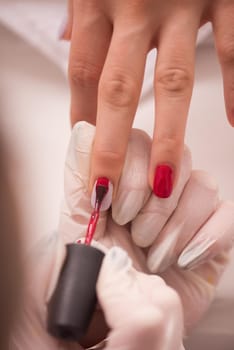 Woman hands receiving a manicure in beauty salon. Nail filing. Close up, selective focus.