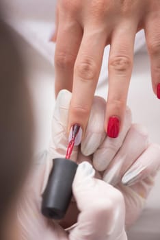 Woman hands receiving a manicure in beauty salon. Nail filing. Close up, selective focus.