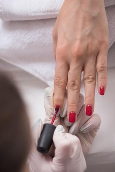 Woman hands receiving a manicure in beauty salon. Nail filing. Close up, selective focus.