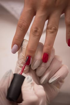 Woman hands receiving a manicure in beauty salon. Nail filing. Close up, selective focus.