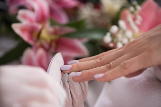 Woman hands receiving a manicure in beauty salon. Nail filing. Close up, selective focus.