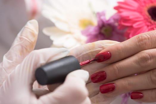 Woman hands receiving a manicure in beauty salon. Nail filing. Close up, selective focus.