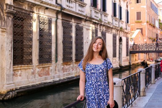 Young girl sitting on banister in Venice, Italy. Concept of last minute tours to Europe and romantic venetsian street.