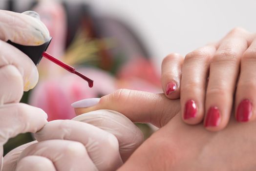 Woman hands receiving a manicure in beauty salon. Nail filing. Close up, selective focus.