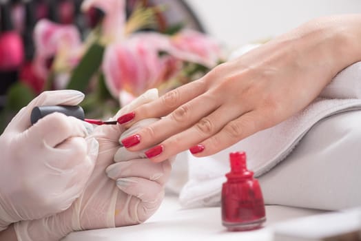 Woman hands receiving a manicure in beauty salon. Nail filing. Close up, selective focus.