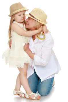 Cute little girl with long blond hair in white dress and hat . The girl girl hugging his neck his grandmother - Isolated on white background