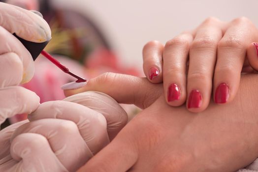 Woman hands receiving a manicure in beauty salon. Nail filing. Close up, selective focus.