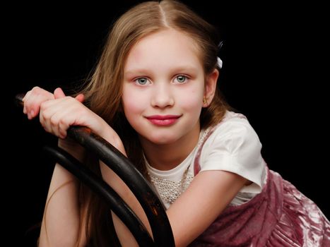 Beautiful little girl, studio portrait on a black background. The concept of a happy childhood, style and fashion.