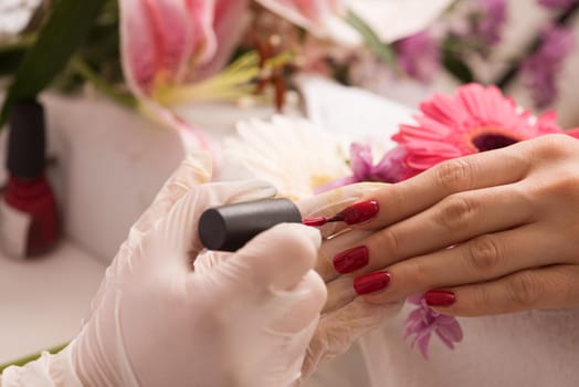 Woman hands receiving a manicure in beauty salon. Nail filing. Close up, selective focus.