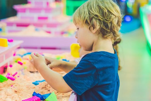 Boy playing with kinetic sand in preschool. The development of fine motor concept. Creativity Game concept.