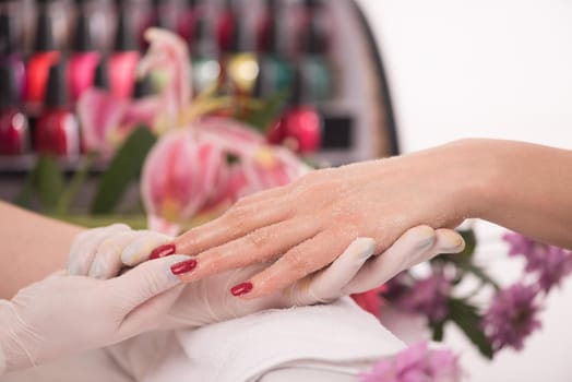 Woman hands receiving a manicure in beauty salon. Nail filing. Close up, selective focus.