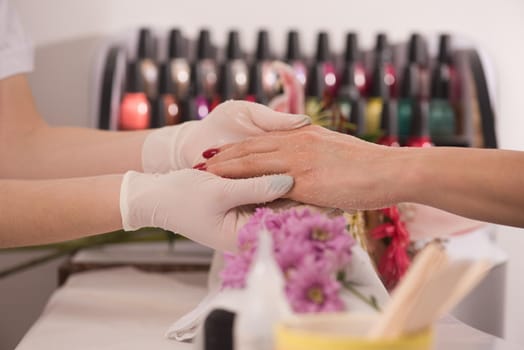 Woman hands receiving a manicure in beauty salon. Nail filing. Close up, selective focus.