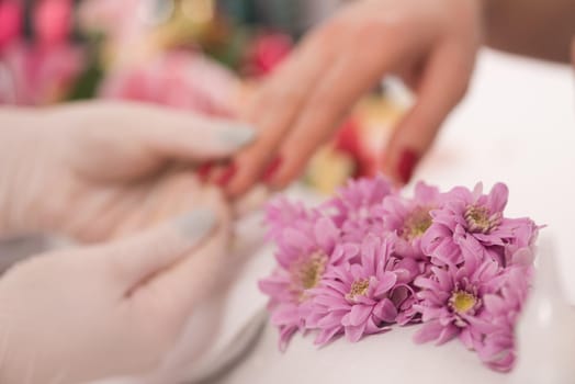 Woman hands receiving a manicure in beauty salon. Nail filing. Close up, selective focus.